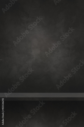 Empty shelf on a black concrete wall. Background template. Vertical backdrop