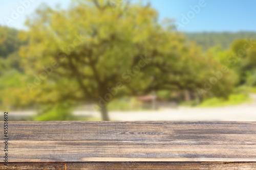 wood table top on blur green tree and blue sky background