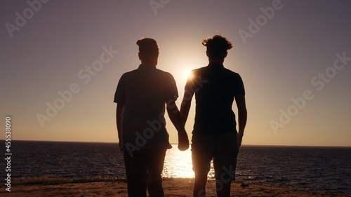 Same-sex couple holding hands  walking on beach together  lgbt love relationship