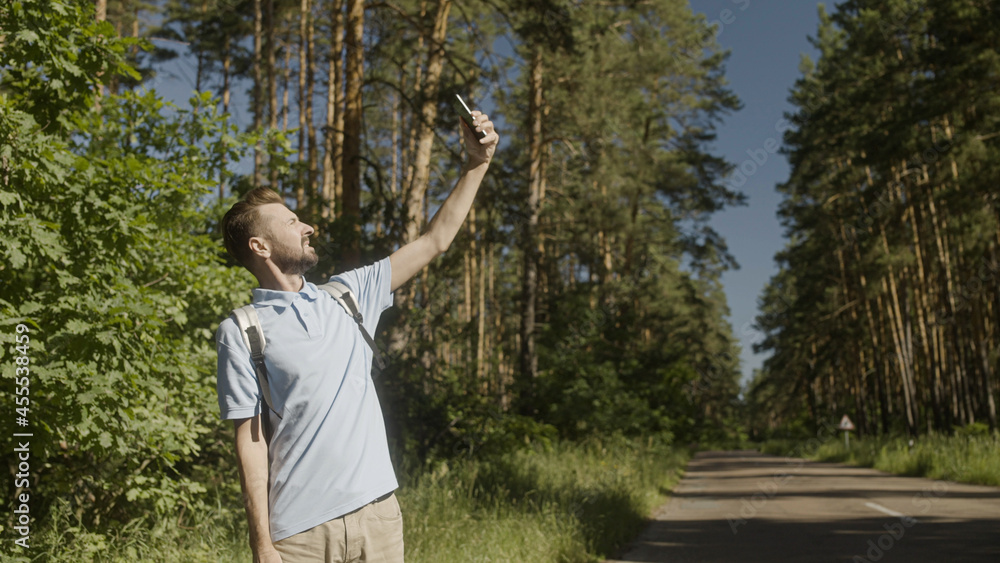 Serious man holding phone up to find mobile network in forest, tourist got lost Serious man holding phone up to find mobile network in forest, tourist got lost