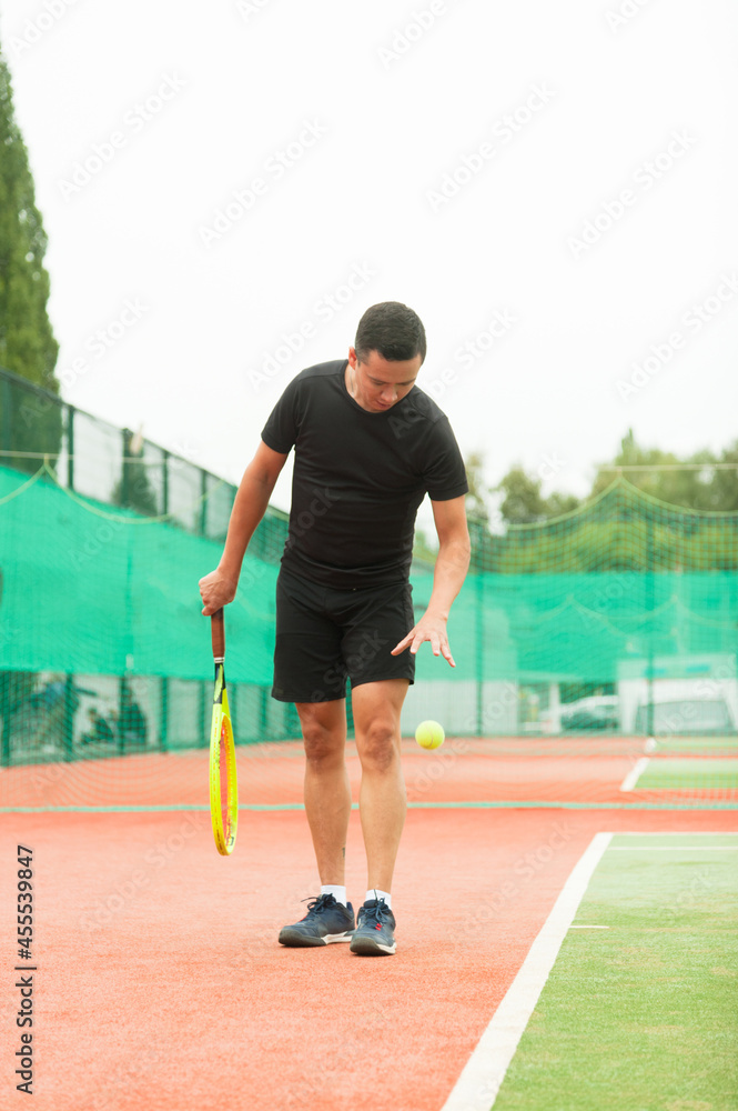 An amateur tennis player to prepare for delivery, on a tennis court with artificial turf.
