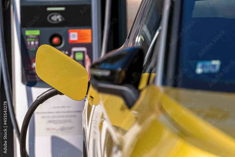 plug of the charging cable plugged into an electric car, charging an electric car at the station plug of the charging cable plugged into an electric car, charging an electric car at the station