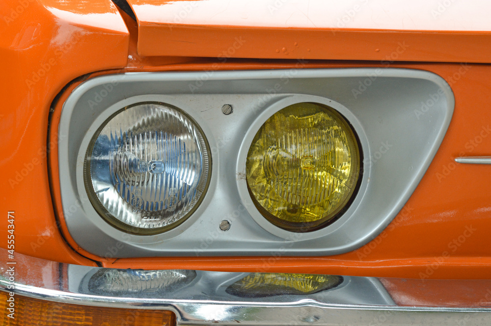 Close-up clear and yellow car's headlight. A retro era when cars used to show off vibrant colors.