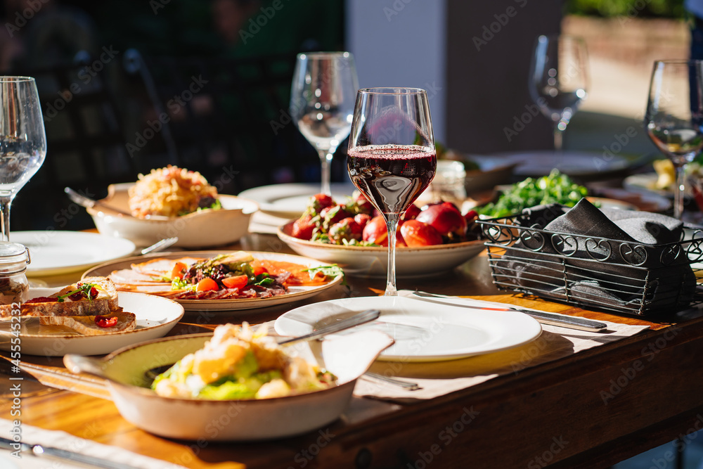 wooden table served with plates with salad and snacks on the open terrace
