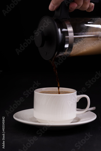 Cup of coffee and a coffee maker on black background