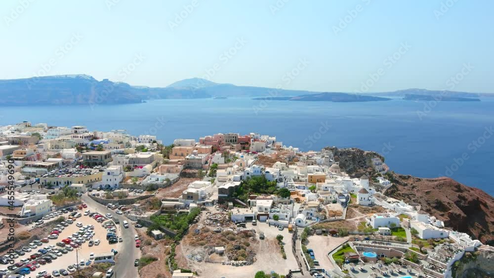 Santorini, Greece: Aerial view of Oia, famous village with iconic white houses on Thira (Thera) island, caldera cliffs towering over Mediterranean Sea - landscape panorama of Europe from above Santorini, Greece: Aerial view of Oia, famous village with iconic white houses on Thira (Thera) island, caldera cliffs towering over Mediterranean Sea - landscape panorama of Europe from above