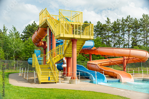 water park slide, bright and colorful red, yellow and orange with background of green pine trees. 