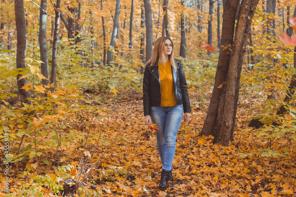 Lonely sad woman is kicking yellow leaves in autumn. Sad mood and seasonal affective disorder concept. Lonely sad woman is kicking yellow leaves in autumn. Sad mood and seasonal affective disorder concept.