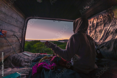 Fototapeta Caucasian guy from United Kingdom enjoying the sunset view from campervan