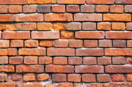 A wall of old crumbling red brick, laid horizontally. Texture for the background.