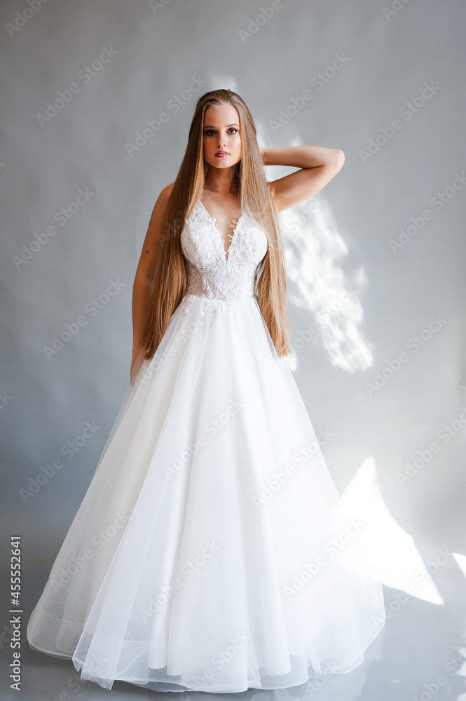 Perfect bride, portrait of a girl in a long white dress. Beautiful hair and clean delicate skin. Wedding hairstyle blonde woman. 