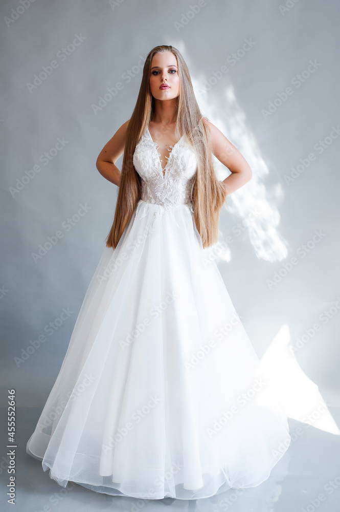 Perfect bride, portrait of a girl in a long white dress. Beautiful hair and clean delicate skin. Wedding hairstyle blonde woman. 