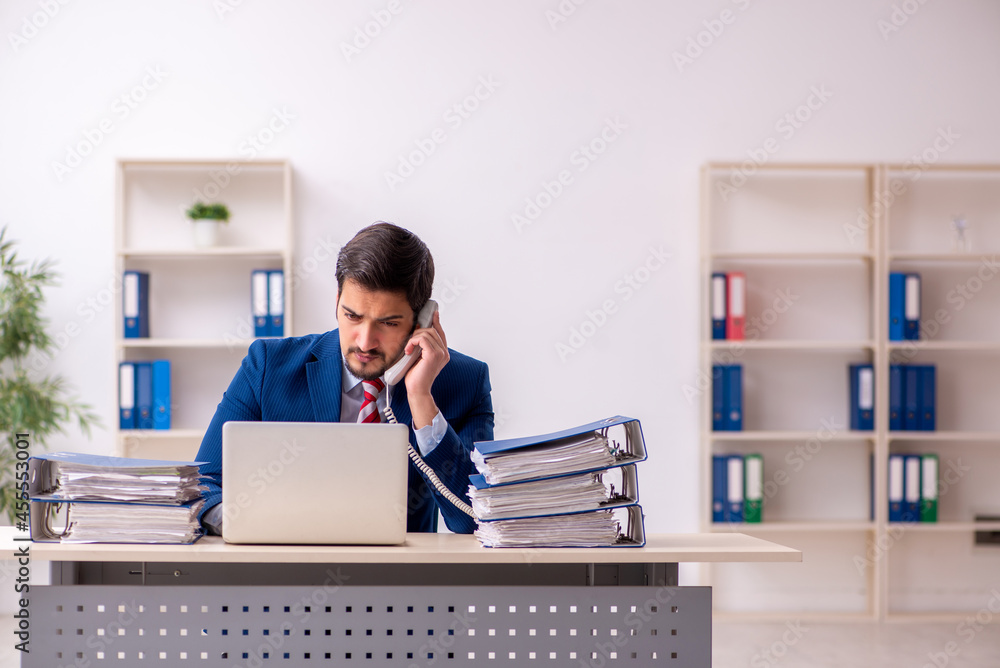 Young male employee unhappy with excessive work in the office Young male employee unhappy with excessive work in the office