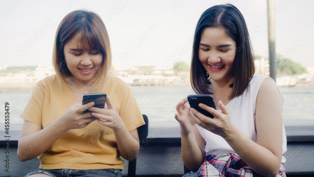 Young Asian women close friend tourist with casual enjoy with smartphone share photo in online social media in front of view port river at cafe city town, Lifestyle tourist travel holiday concept. Young Asian women close friend tourist with casual enjoy with smartphone share photo in online social media in front of view port river at cafe city town, Lifestyle tourist travel holiday concept.
