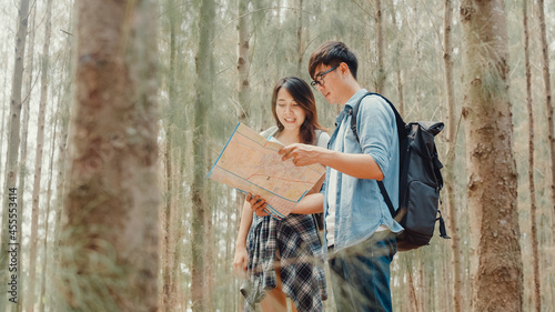 Asian hiker couple trekking in forest. Young happy backpack male and female walking enjoy her journey, travel nature and adventure trip, climb mountain lot of tree in fall holidays vacation concept.