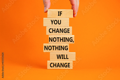 Change symbol. Wooden blocks with words 'If you change nothing, nothing will change'. Businessman hand. Beautiful orange background, copy space. Business, motivation and changes concept. photo