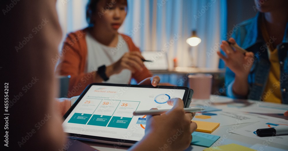 Close-up asia businesspeople meeting plan analysis statistics brainstorm and header of team hold tablet point graph chart and employee take note at home office night. Finance strategy success concept.