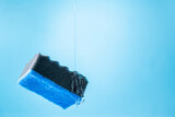 Kitchen dish washing sponge and dish washing liquid on blue background. Household cleaning scrub sponges with cleaning gel. Cleaning home concept. Copy space