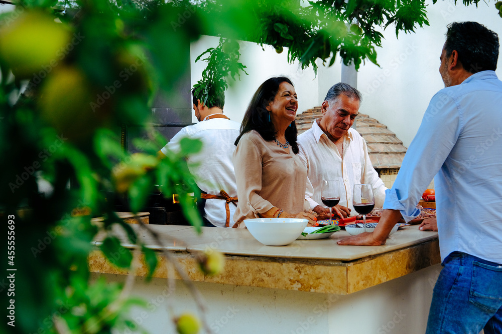 Senior couple talking while having wine with family in backyard during weekend Senior couple talking while having wine with family in backyard during weekend
