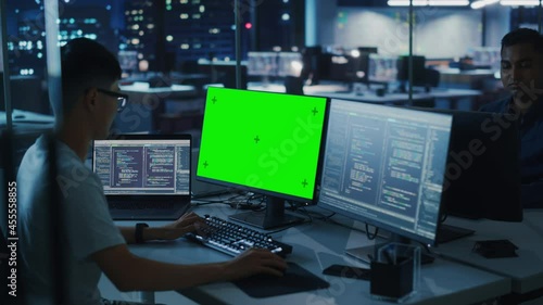 Wallpaper Mural Night Office: Young Japanese Man in Working on Green Screen Chroma Key Desktop Computer. Team of Programmers Typing Code, Creating Modern Software, e-Commerce App Design, e-Business Programming Torontodigital.ca