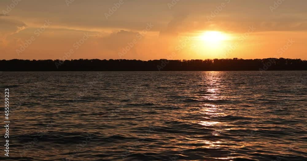 Sunset on the banks of the river, the sun sets in small thunderclouds. Warm summer evening. Sunset on the banks of the river, the sun sets in small thunderclouds. Warm summer evening.