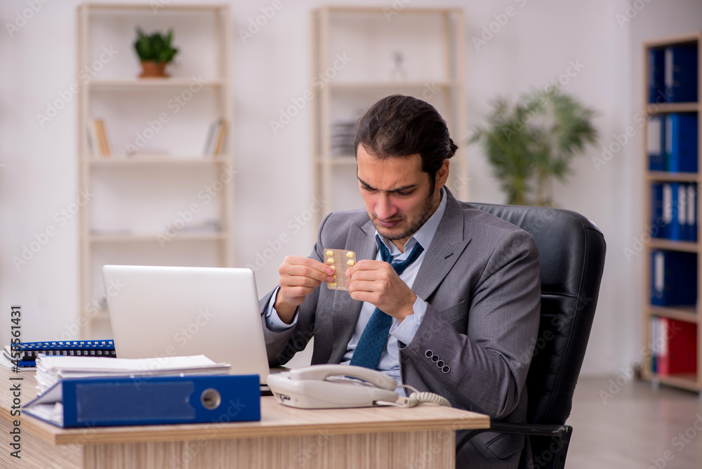 Young male sick employee working in the office Young male sick employee working in the office