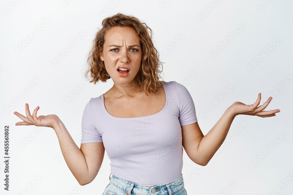 So what. Arrogant blond girl spread hands sideways and shrugging annoyed, cant understand something, confused and pissed-off, white background So what. Arrogant blond girl spread hands sideways and shrugging annoyed, cant understand something, confused and pissed-off, white background