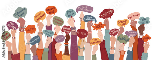 Many arms raised of diverse and multi-ethnic people holding speech bubbles with text -Merry Christmas- in various international languages. People diversity. Christmas greetings. Equality