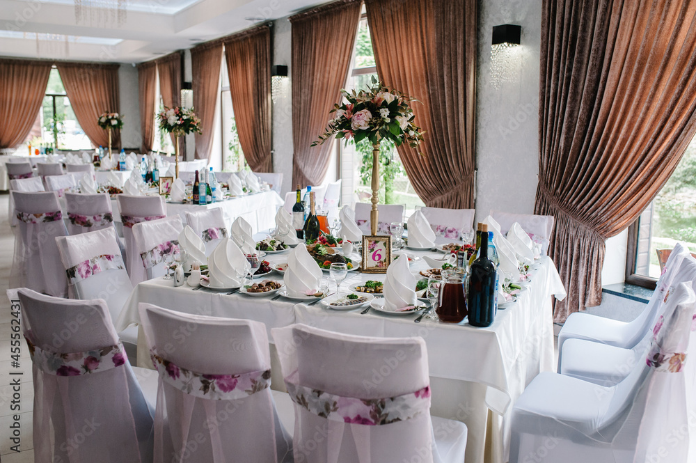 A composition of flowers and green is on a festive table at the wedding banquet hall. Stands, sign number. Close up. A composition of flowers and green is on a festive table at the wedding banquet hall. Stands, sign number. Close up.