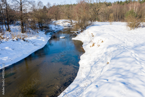 Drone shot flying on forest and river in winter. © yauhenka