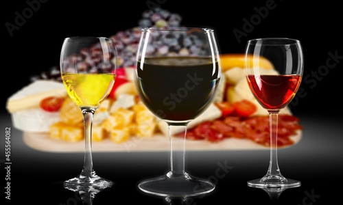 Glasses of red, white and rose wine over a delicatessen table in the background