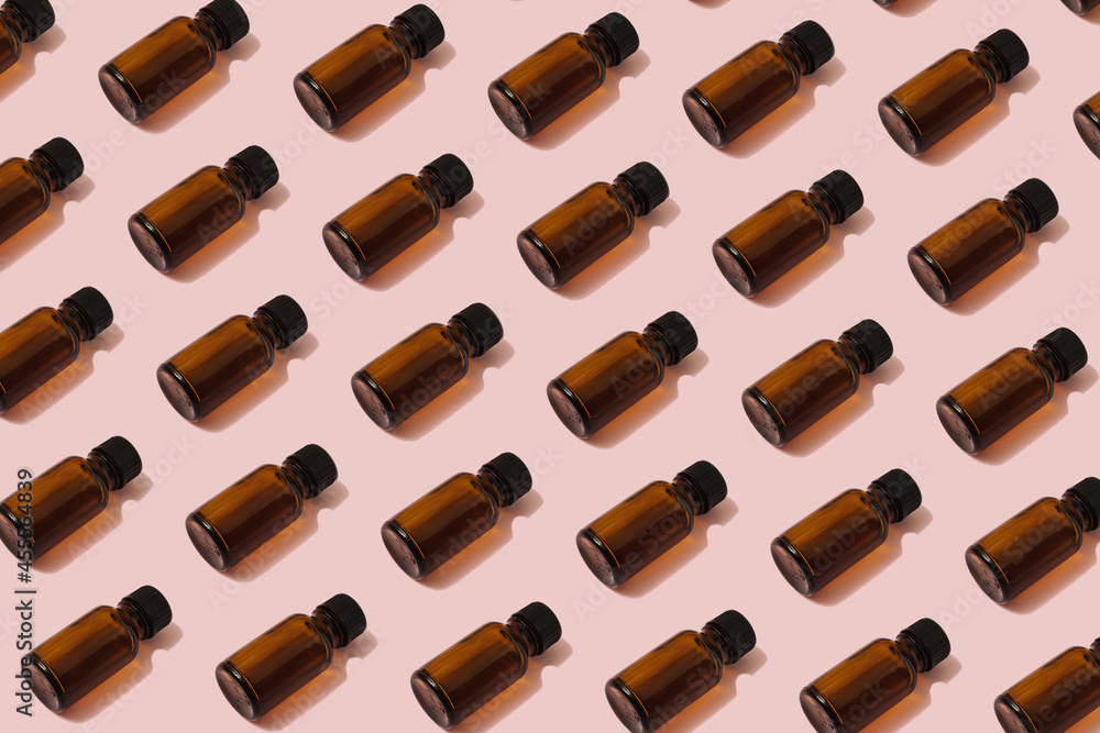 Trendy sunlight beauty pattern made with brown glass cosmetic bottles on vibrant pastel pink background. Eco friendly self care and wellness concept. Trendy sunlight beauty pattern made with brown glass cosmetic bottles on vibrant pastel pink background. Eco friendly self care and wellness concept.
