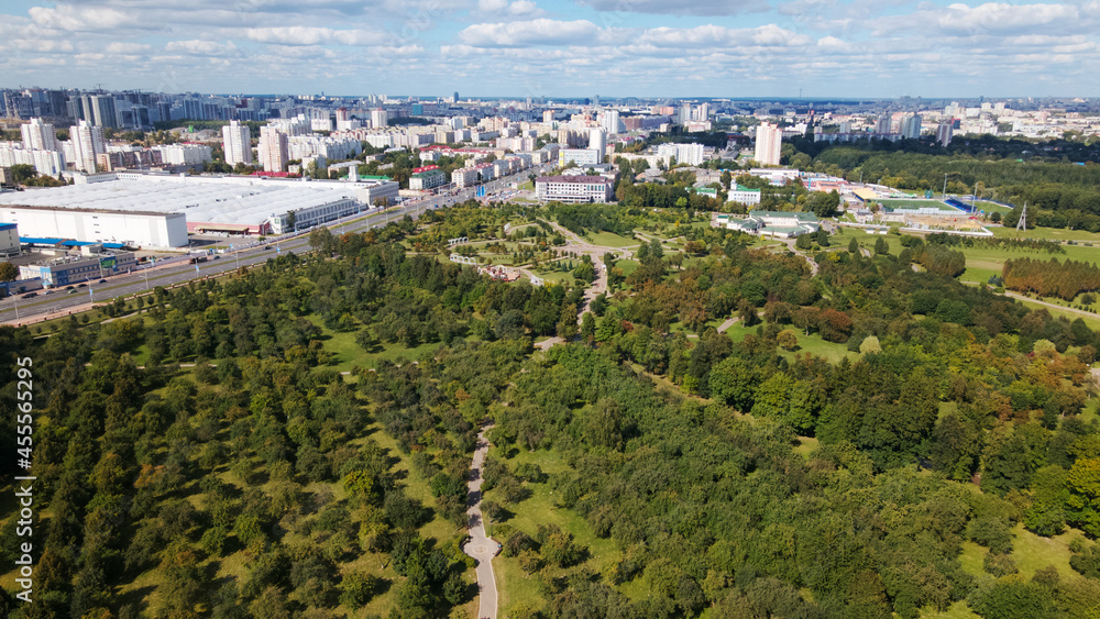Obraz premium City landscape. Nearby there is a park area. Blue sky with white clouds. Aerial photography.