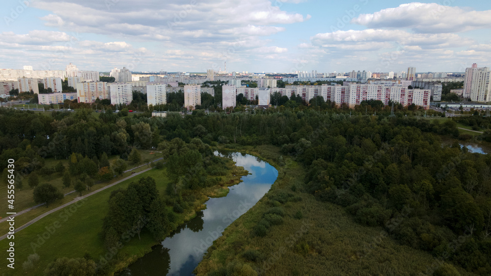 Fototapeta premium City landscape. Nearby there is a park area. Blue sky with white clouds. Aerial photography.