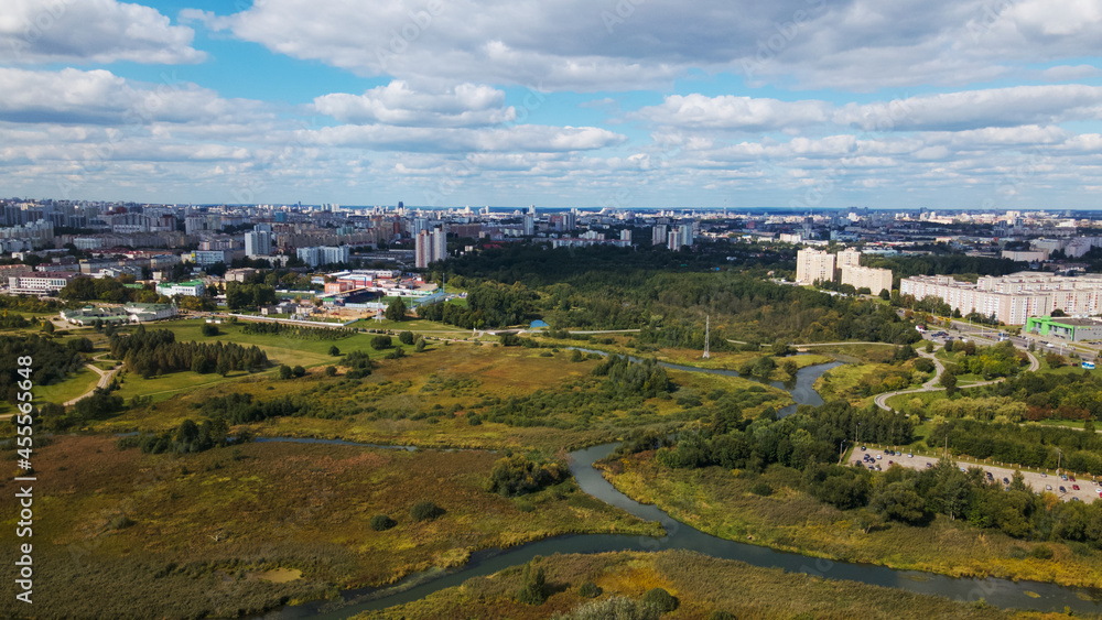 City landscape. Nearby there is a park area. Blue sky with white clouds. Aerial photography.