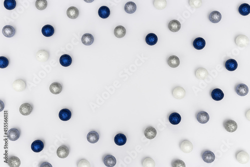 Bright winter holiday frame with sparkling silver and blue balls on white background with copy space.