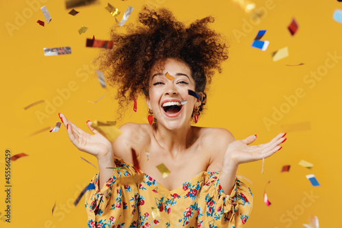 Canvastavla Young happy satisfied excited fun surprised amazed woman 20s with culry hair in casual clothes tossing throwing confetti isolated on plain yellow background studio portrait