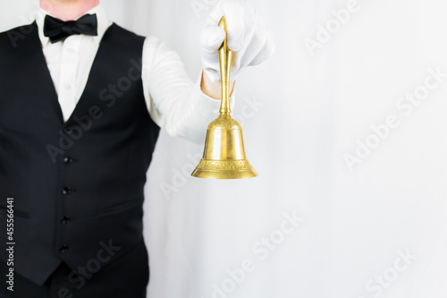 Portrait of Butler or Waiter in White Gloves Holding Gold Bell on White Background. Copy Space for Service Industry and Professional Hospitality. 