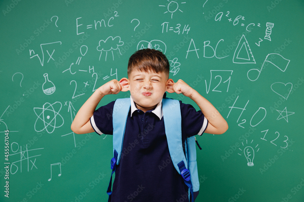 Young fun male kid school boy 5-6 years old in t-shirt backpack show ears fooling around isolated on green wall chalk blackboard background studio. Childhood children kids education lifestyle concept Young fun male kid school boy 5-6 years old in t-shirt backpack show ears fooling around isolated on green wall chalk blackboard background studio. Childhood children kids education lifestyle concept