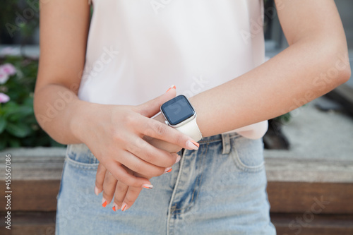 Woman standing on the street with a smart watch in her hand.