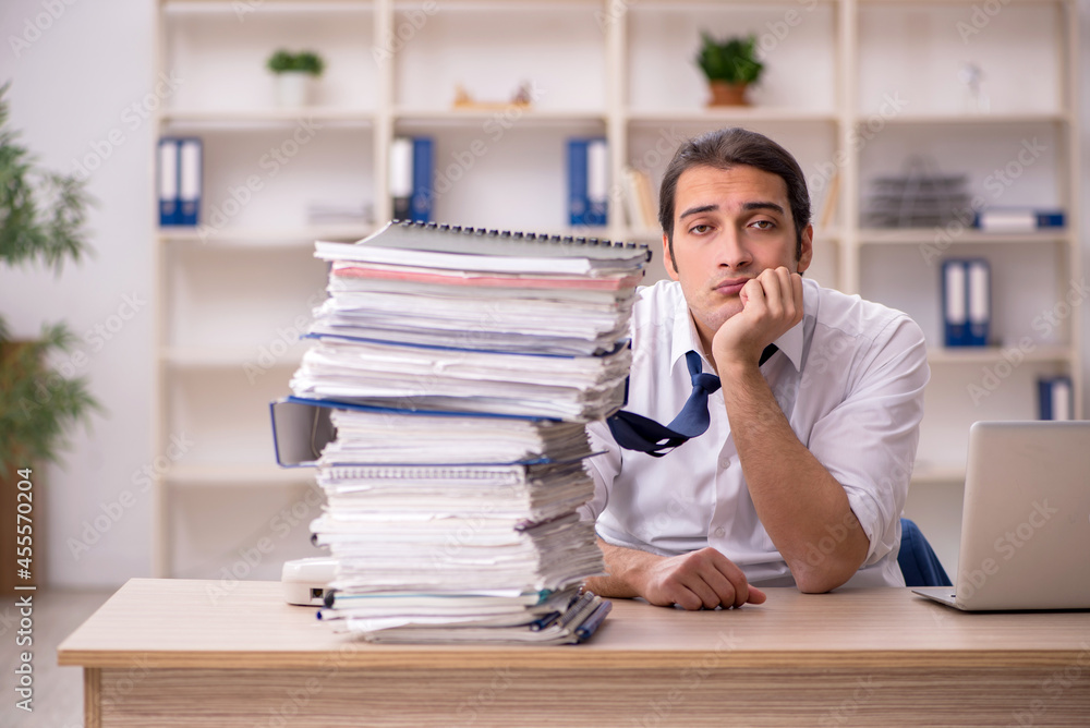 Young male employee and a lot of work in the office Young male employee and a lot of work in the office
