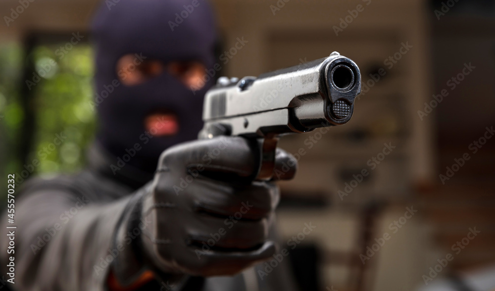 Robber with balaclava holds gun in leather gloved hand. Weapon, crime. Robber with balaclava holds gun in leather gloved hand. Weapon, crime.