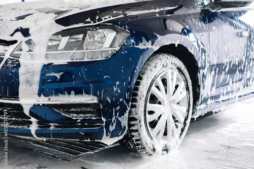 Manual car wash with white soap, foam on the body. Washing Car Using High Pressure Water.