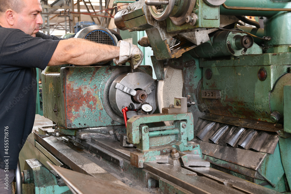 The worker clamps the part in the chuck of the grinder for grinding.