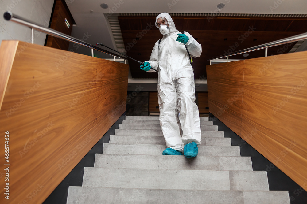 A photo shot of a man in a white uniform suppressing a Coronavirus germ of indoor public stairs. Stay healthy A photo shot of a man in a white uniform suppressing a Coronavirus germ of indoor public stairs. Stay healthy