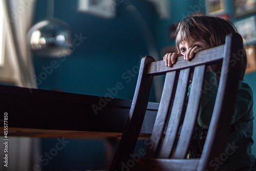 Boy standing behind wooden chair