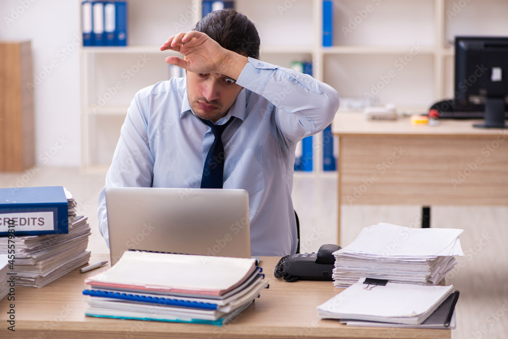 Young male employee and too much work in the office Young male employee and too much work in the office