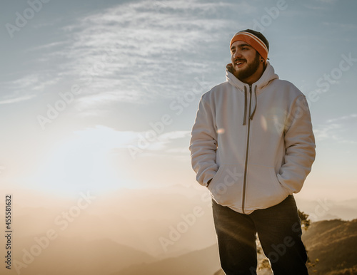 Man in offwhite jacket and colorful kint cap standing high in the mountain photo