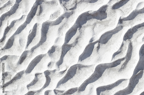 Gray texture background of Pamukkale calcium travertine in Turkey, pattern of diagonal waves, close-up. © Anna Sitnik