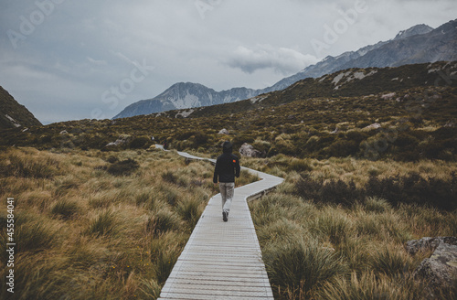 Person walking on a wooden walkway near mountains photo